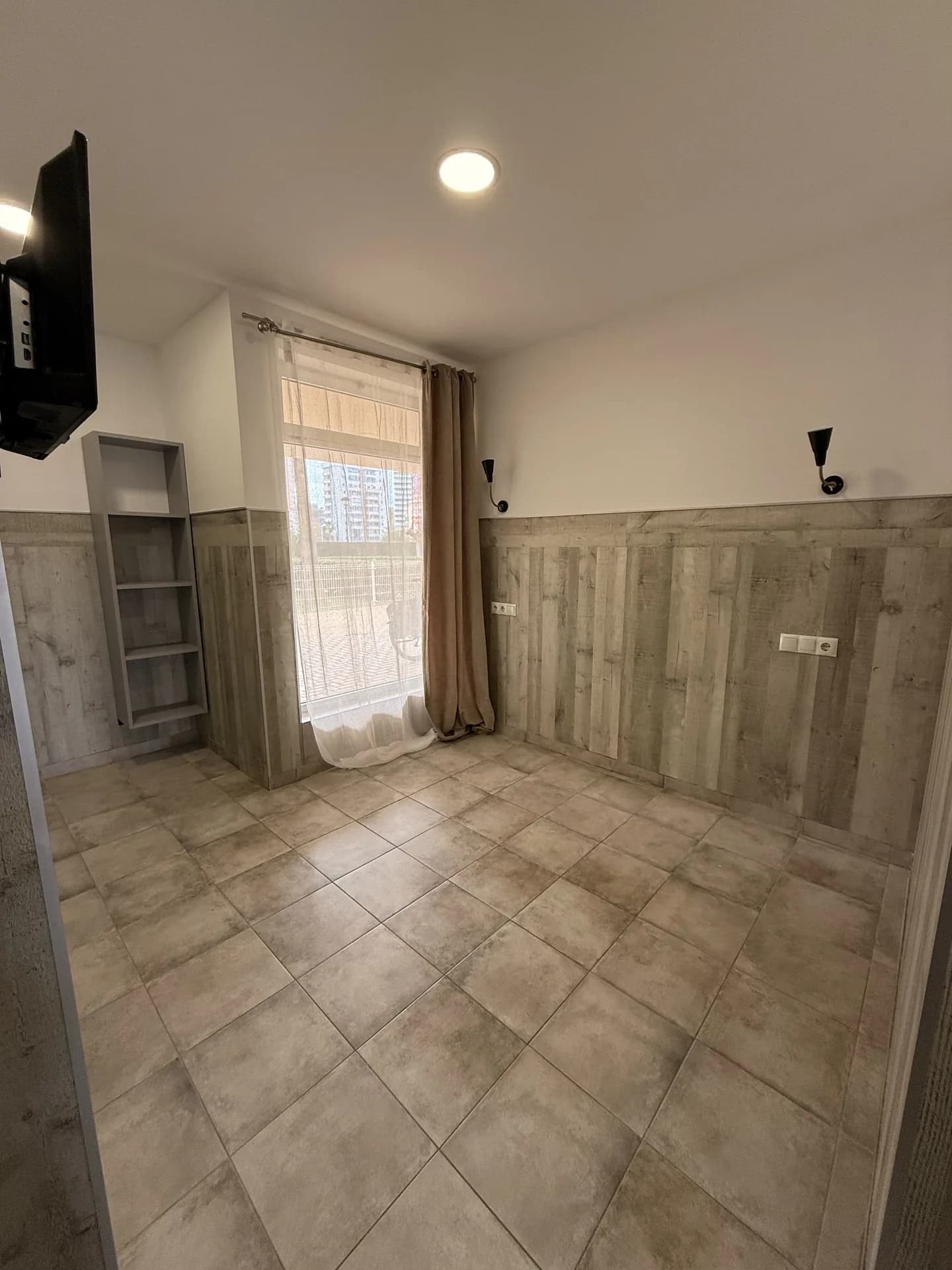 One of the rentable rooms at Almorada Rosal, with tiled floor and a wall-mounted TV