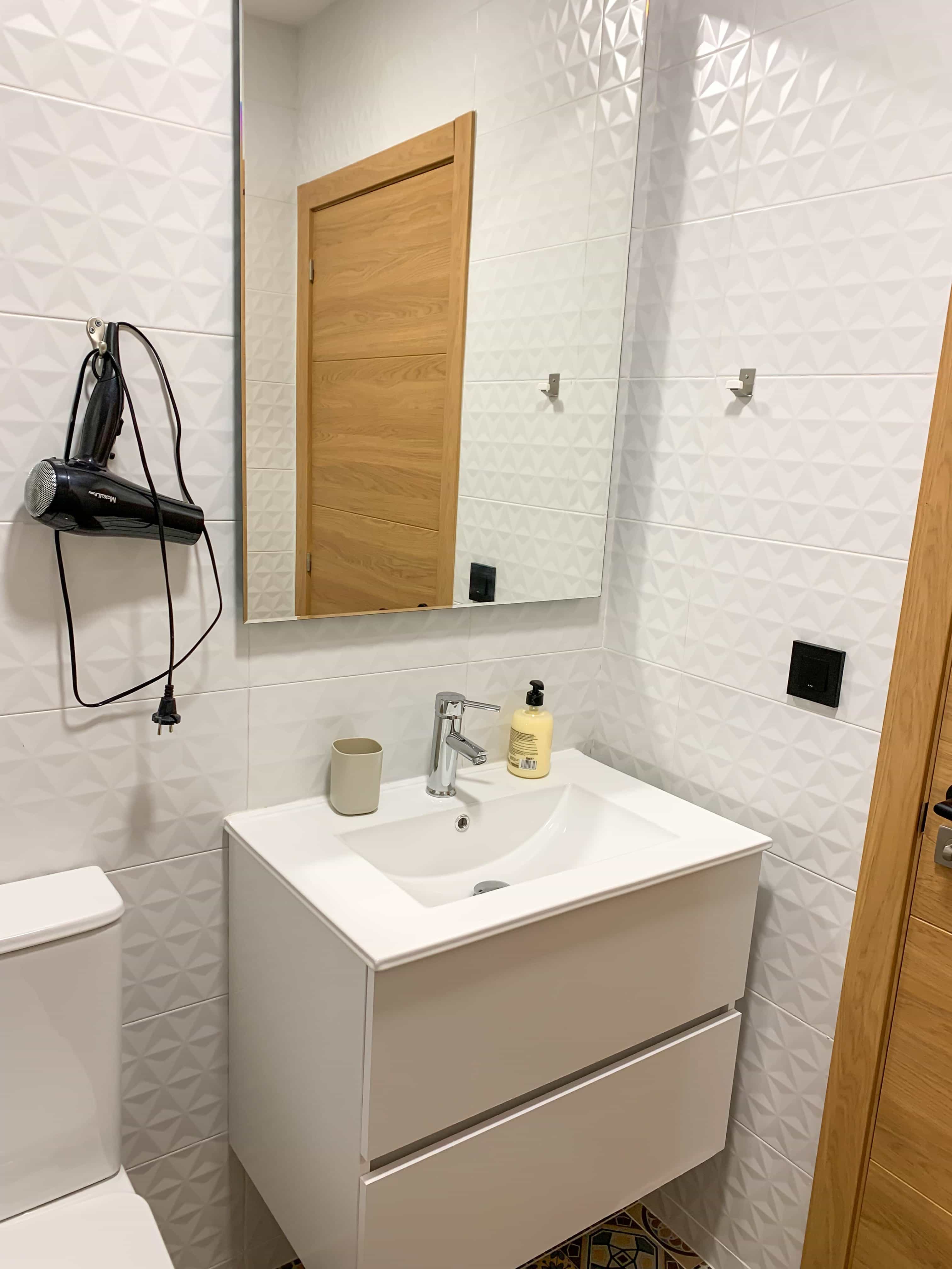 The bathroom in a La Ruta studio, with a vanity, mirror and hairdryer