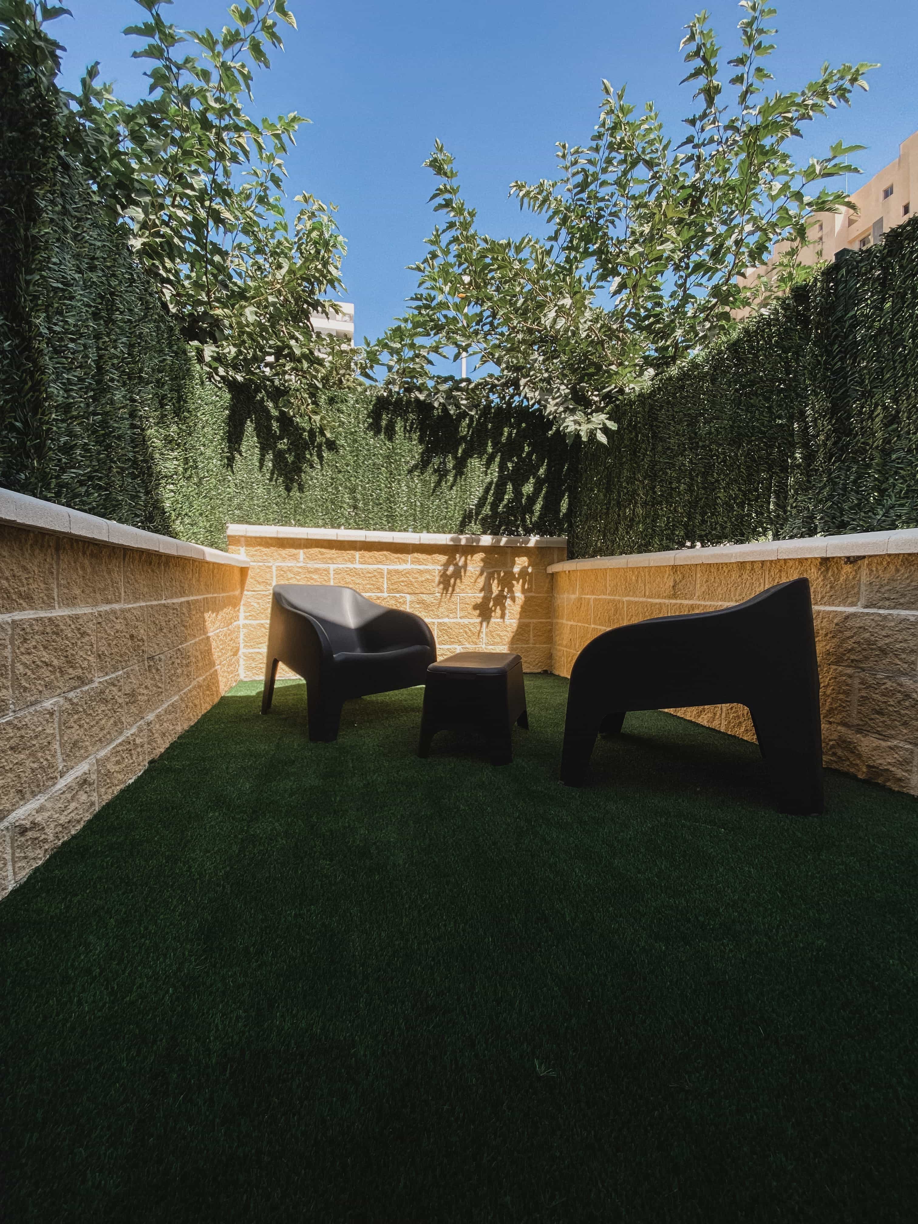 The private patio of a La Ruta studio, hedged in and furnished with lounge seating