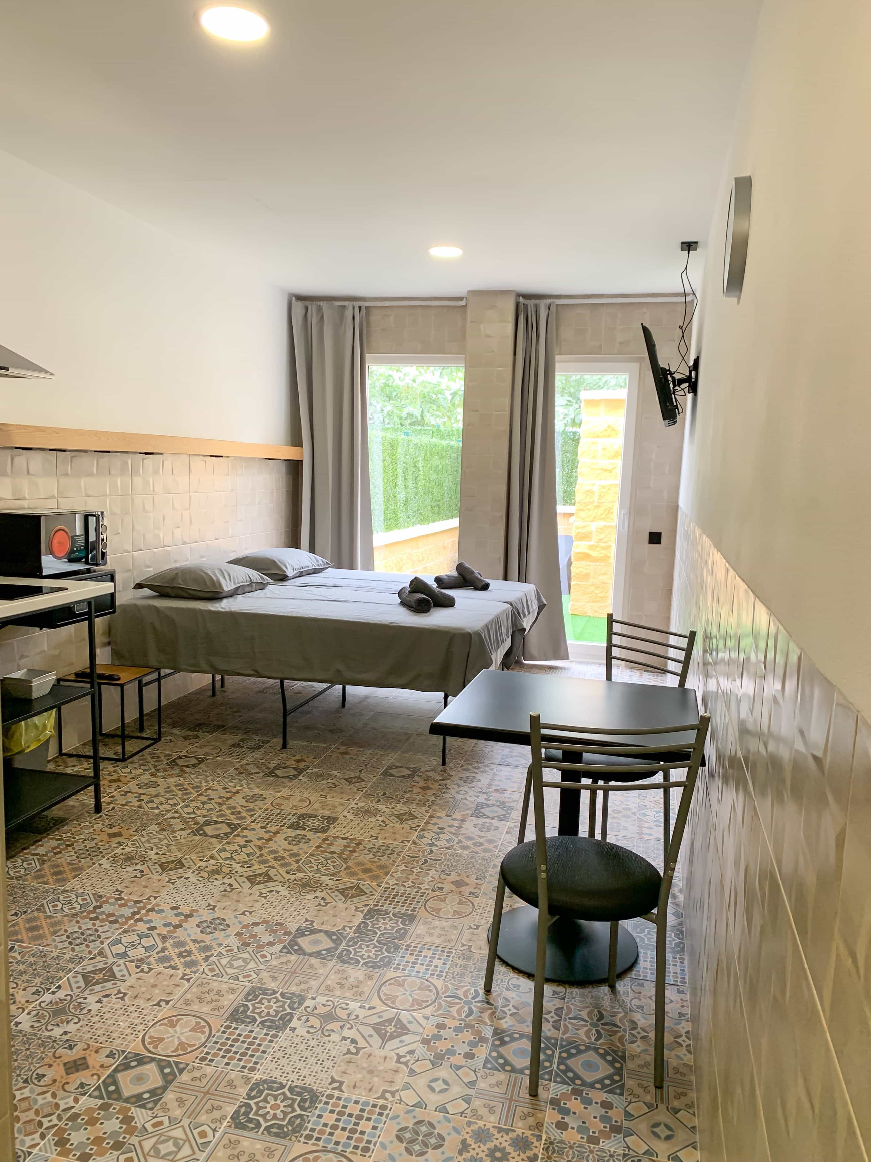 A studio at Hotel Apartamentos La Ruta, with the bed beside the kitchenette and the patio doors open to the garden