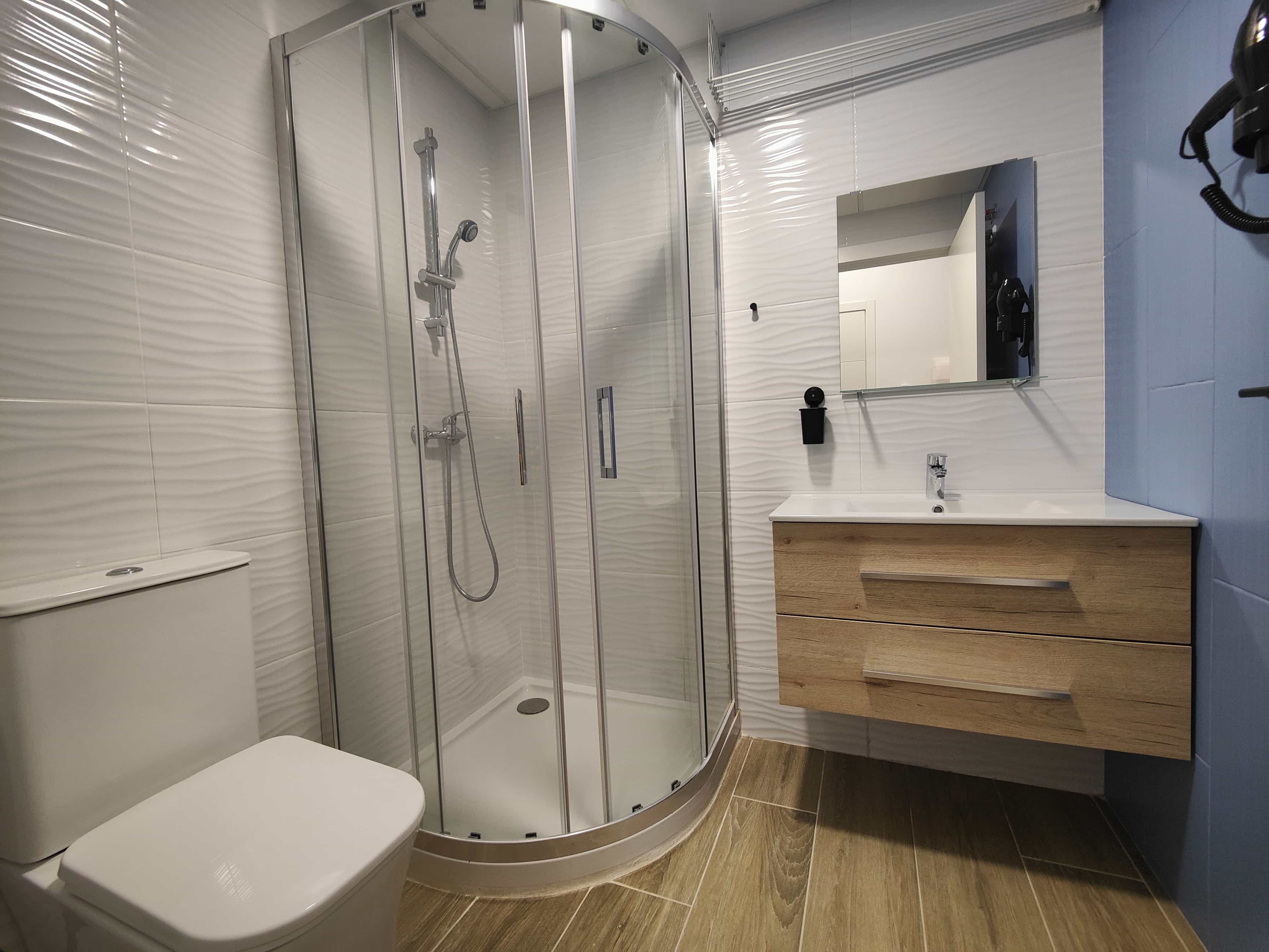 The bathroom in a Pueblo Mar studio, with a corner shower and a wood-look vanity
