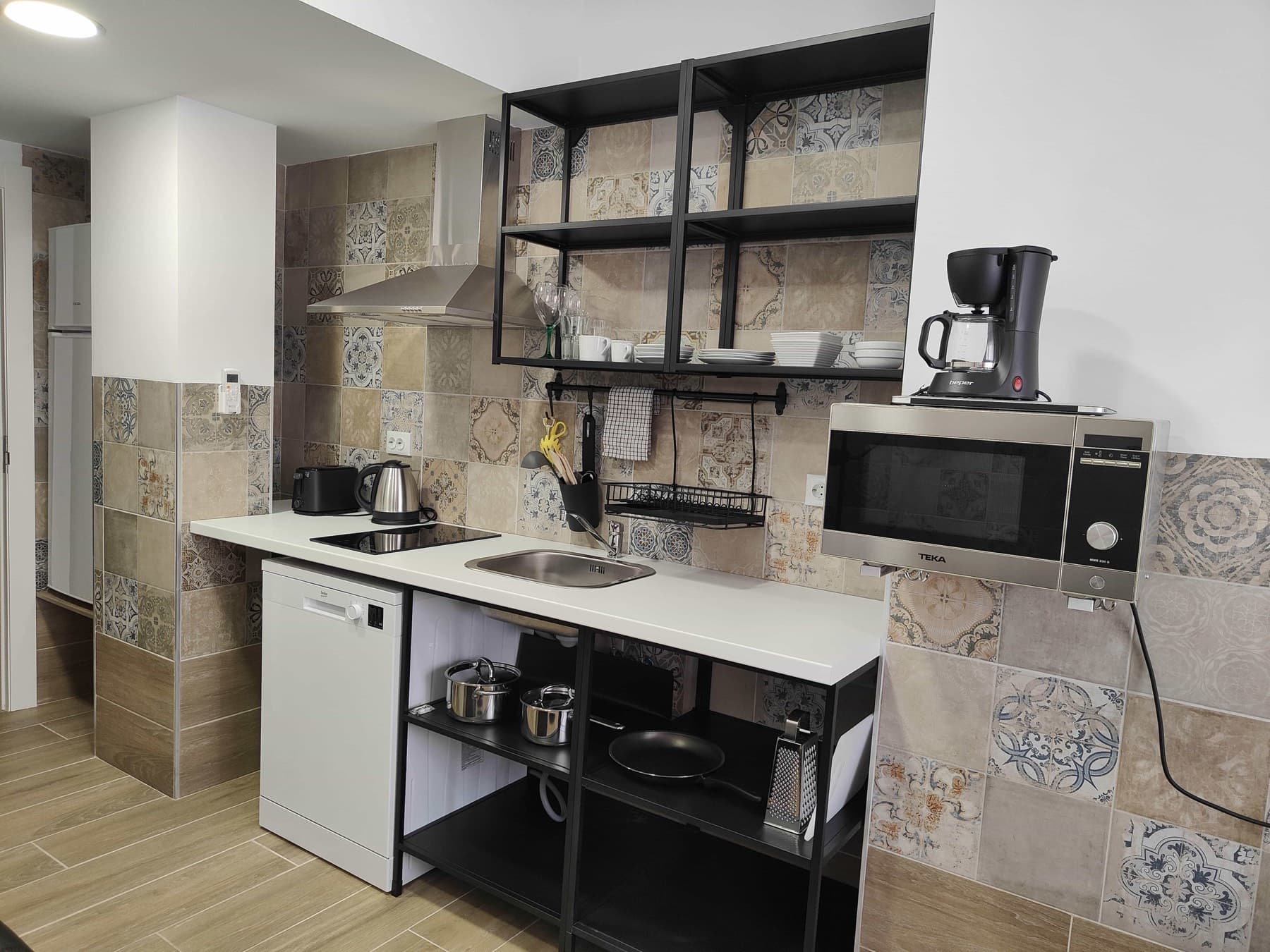 The kitchenette in a Pueblo Mar studio, with open shelving, a dishwasher and a hob